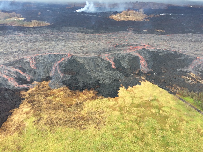 Aerial photograph of some minor overflows of the upper fissure 8 lava that sent small flows of lava down the levee walls. These overflows did not extend far from the channel and hence did not pose and immediate threat to nearby areas. Channel overflows like the ones shown here add layers of lava to the channel levees, increasing their height and thickness. (HVO/USGS)