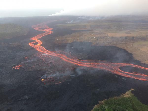 The fissure 8 channel continues to carry lava toward the coast on the west side of Kapoho Crater (vegetated cone, far left). Northwest of this cone, overflows (lower left) of the channel occurred overnight, but lava was confined to the existing flow field and did not threaten any homes or structures. (image 23 July: HVO / USGS)
