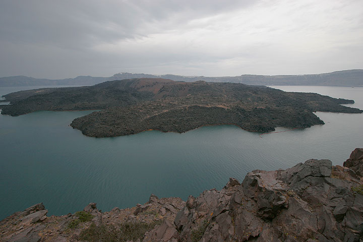 Nea Kameni island, the site of the last eruptions, with its lava flows in the caldera of Santorini volcano, seen on a cloudy day from Palea Kameni