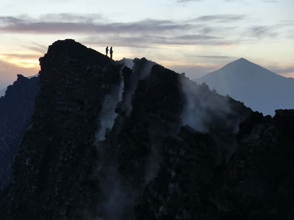 Watching the sun rise between Mikeno and Karisimbi from he rim of Nyiragongo´s summit caldera