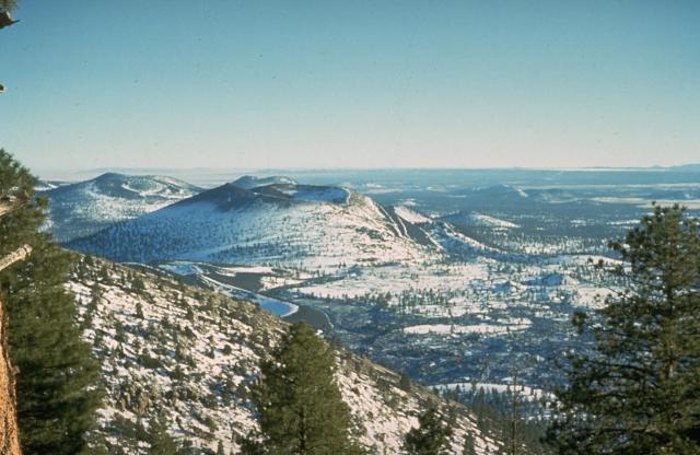 Snow-mantled Sunset Crater (left-center), seen from O'Leary Peak to the NW, is the youngest volcanic feature of the San Francisco Mountain volcanic field, which covers a vast area of northern Arizona between Flagstaff and the Grand Canyon. The Sunset Crater eruption began about 1100 AD from a chain of cinder cones and vents trending NW-SE, the largest of which is Sunset Crater. Three lava flows were erupted, the longest of which traveled 11 km to the NE. Photo by Ed Wolfe, 1973 (U.S. Geological Survey)