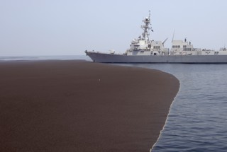 Large floating ash and pumice rafts resulted from the 30 September 2007 eruption of Jebel at Tair. One of these rafts can be seen in this photo with the USS Bainbridge about 20 km from the island on 2 October 2007. Photo by MCpl Kevin Paul, Canadian Forces Combat Camera.
