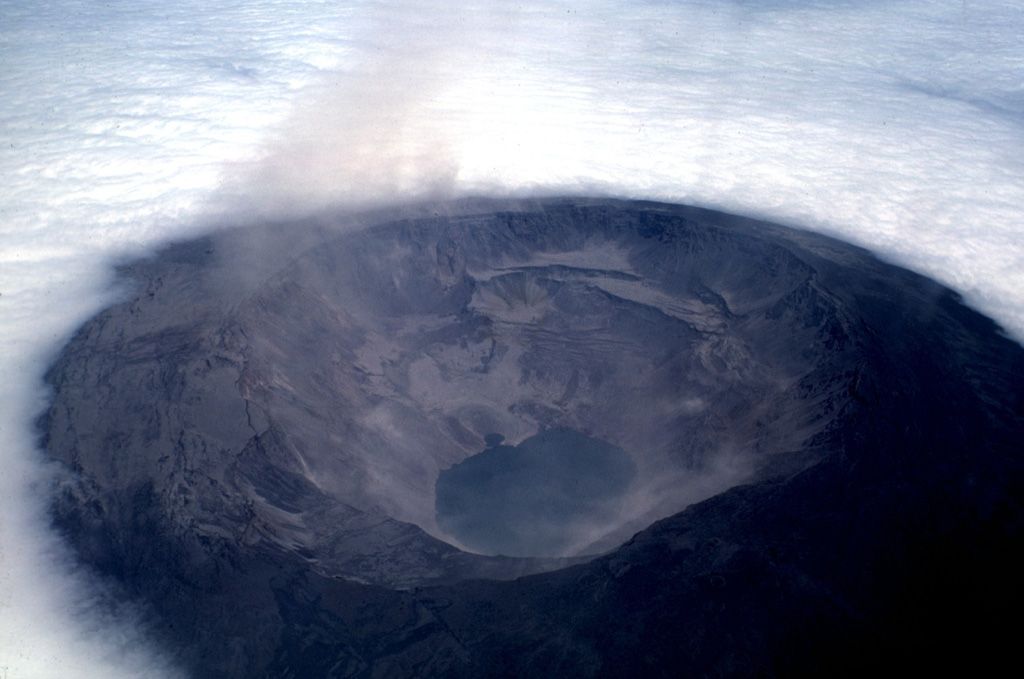 The Fernandina caldera seen on July 4, 1968, about three weeks after a major explosive eruption that was followed by collapse of the caldera floor. Collapse occurred incrementally and asymmetrically, ranging up to about 350 m at the SE end of the caldera, which contains the caldera lake. Photo by Tom Simkin, 1968 (Smithsonian Institution).