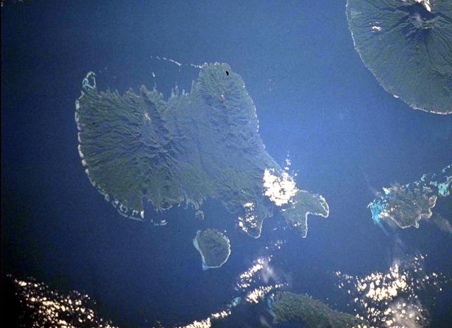 Vella Lavella Island (left center) in the New Georgia Islands in the Solomon Islands chain. North lies to the upper left in this NASA Space Shuttle image. Nonda volcano, the youngest volcanic feature of Vella Lavella Island, is a lava dome located within a well-preserved crater in the northern part of the island. The Paraso thermal area, the small light-colored area at the upper left-center portion of the island, displays solfataras, hot springs, and boiling mud pots. Kolombangara Island is at the upper right. (NASA Space Shuttle image ISS002-727A-2, 2001)